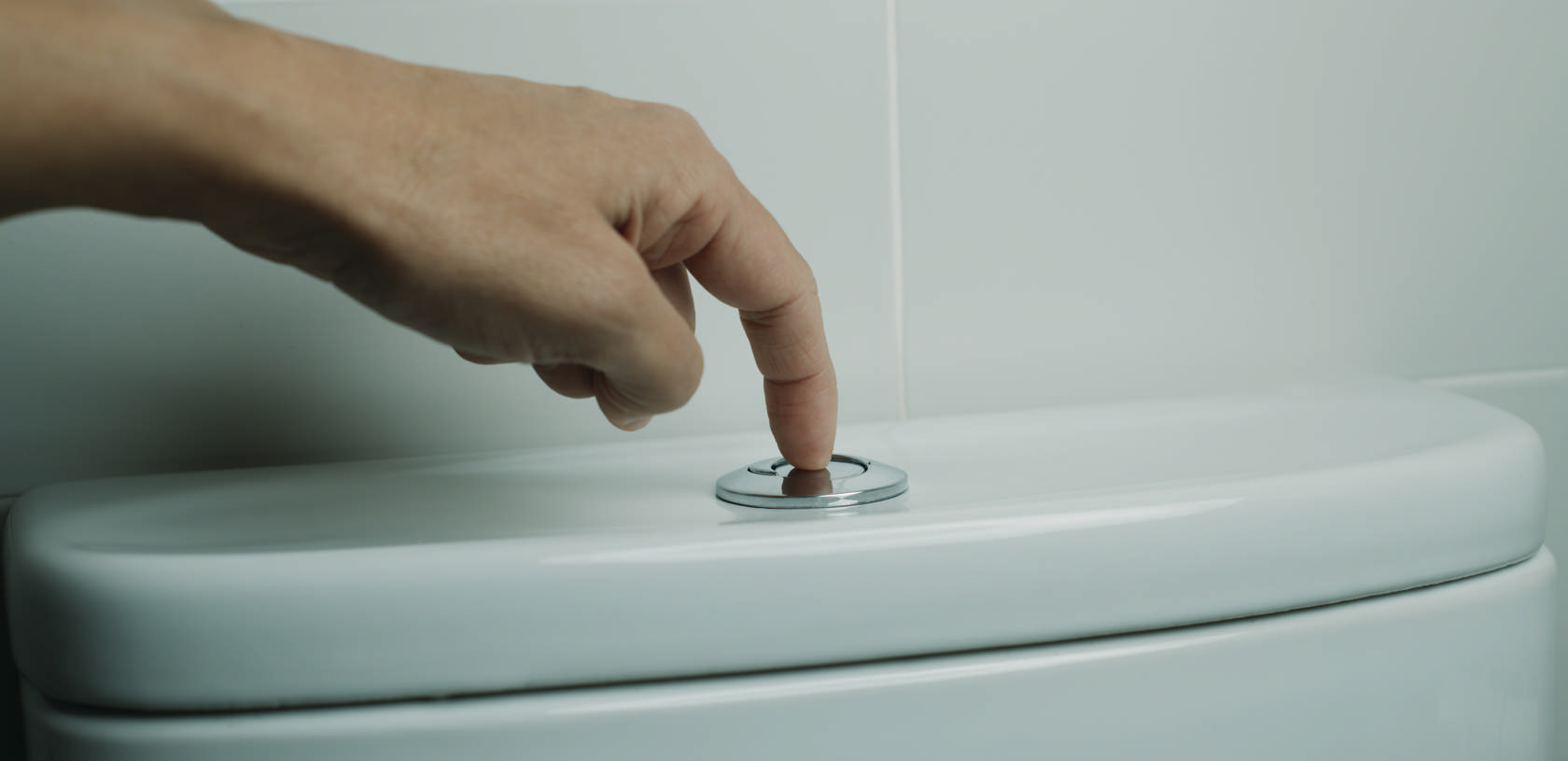 Billedet viser en hånd, som aktiverer skyl på et toilet. Foto: Colourbox.